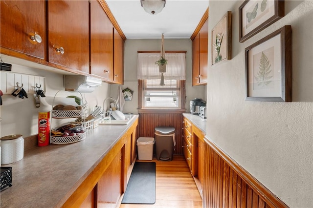93 Pleasant St, Cranston, RI 02910 - kitchen featuring brown cabinets, light wood finished floors, a sink, light countertops, and a wainscoted wall