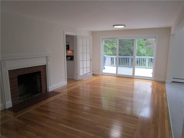 524 Middle Rd, East Greenwich, RI 02818 - unfurnished living room with wood finished floors, a baseboard radiator, a brick fireplace, and baseboards