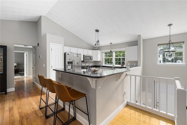 299 S Christopher Ave, Tiverton, RI 02878 - kitchen featuring appliances with stainless steel finishes, white cabinets, a sink, light wood finished floors, and a kitchen breakfast bar