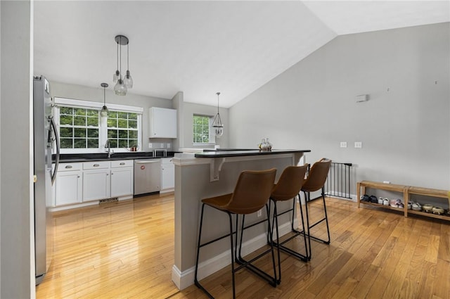 299 S Christopher Ave, Tiverton, RI 02878 - kitchen featuring appliances with stainless steel finishes, lofted ceiling, a kitchen bar, white cabinetry, and light wood-style flooring