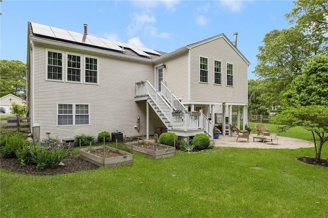 299 S Christopher Ave, Tiverton, RI 02878 - back of house with a patio area, a vegetable garden, roof mounted solar panels, a lawn, and stairs