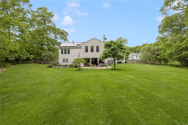 299 S Christopher Ave, Tiverton, RI 02878 - back of property featuring a patio area, a chimney, roof mounted solar panels, and metal roof