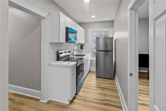 1413 Broad St, Providence, RI 02905 - kitchen featuring stainless steel appliances, light countertops, light wood finished floors, white cabinets, and recessed lighting