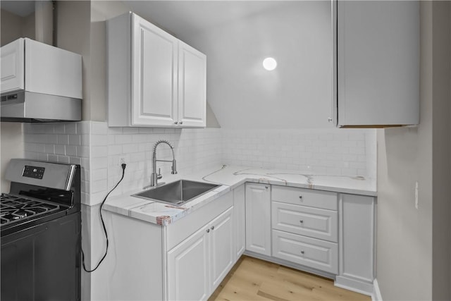 1413 Broad St, Providence, RI 02905 - kitchen with stainless steel gas range oven, a sink, light wood-type flooring, white cabinets, and decorative backsplash