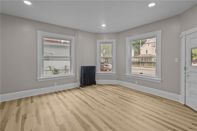 1413 Broad St, Providence, RI 02905 - unfurnished living room with radiator heating unit, light wood-style floors, baseboards, and recessed lighting