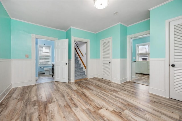 130 Alice Ave, Woonsocket, RI 02895 - empty room with wainscoting, light wood-style flooring, ornamental molding, stairway, and a baseboard heating unit