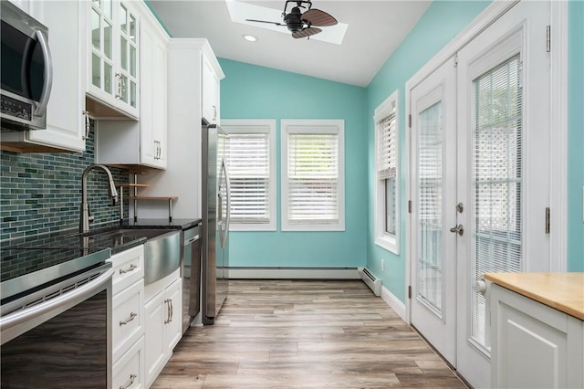 130 Alice Ave, Woonsocket, RI 02895 - kitchen with appliances with stainless steel finishes, a skylight, lofted ceiling, decorative backsplash, and plenty of natural light