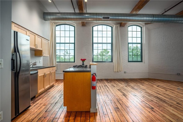 28 Bayley St Unit 304, Pawtucket, RI 02860 - kitchen featuring appliances with stainless steel finishes, brick wall, light wood-style flooring, dark countertops, and beam ceiling