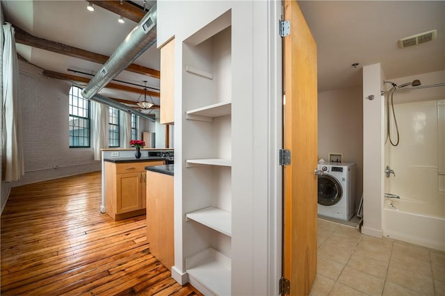 28 Bayley St Unit 304, Pawtucket, RI 02860 - interior space with open shelves, washer / dryer, dark countertops, beamed ceiling, and brick wall
