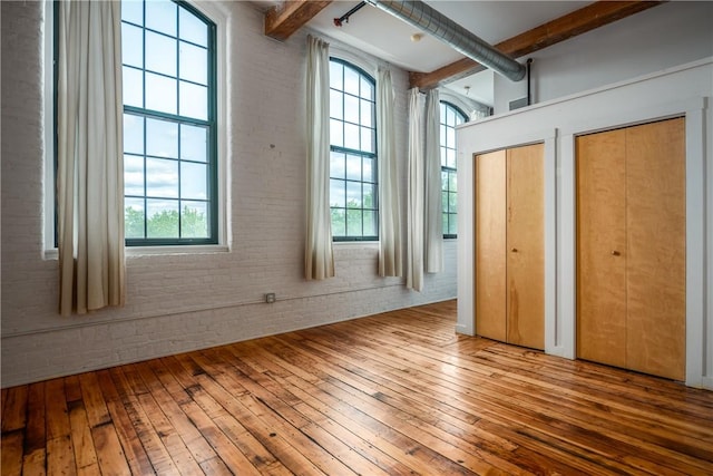28 Bayley St Unit 304, Pawtucket, RI 02860 - unfurnished bedroom featuring hardwood / wood-style floors, beamed ceiling, two closets, and brick wall