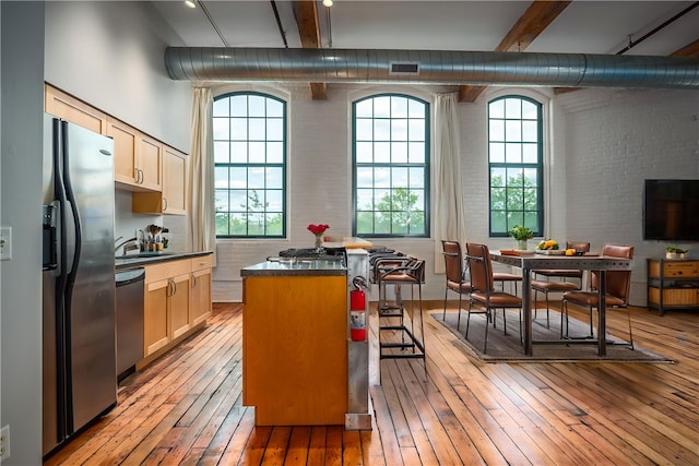 28 Bayley St Unit 304, Pawtucket, RI 02860 - kitchen with appliances with stainless steel finishes, light wood-style flooring, beam ceiling, brick wall, and dark countertops