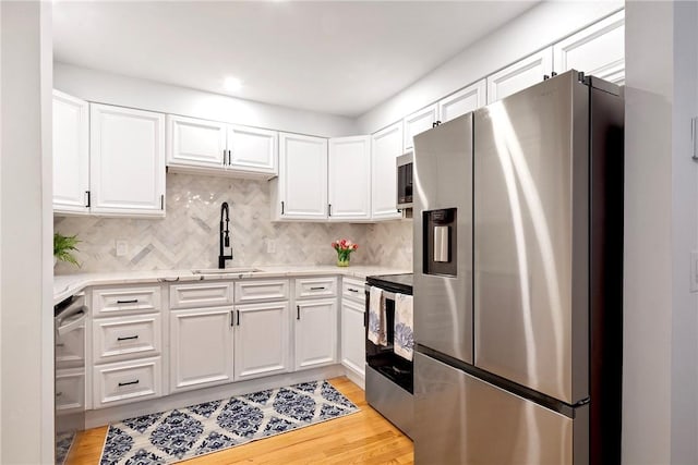 75 Pelham St Unit A, Newport, RI 02840 - kitchen with stainless steel appliances, a sink, white cabinetry, and light wood finished floors