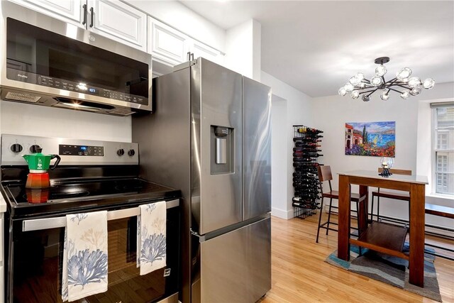 75 Pelham St Unit A, Newport, RI 02840 - kitchen featuring stainless steel appliances, a chandelier, light wood-style floors, white cabinetry, and baseboards