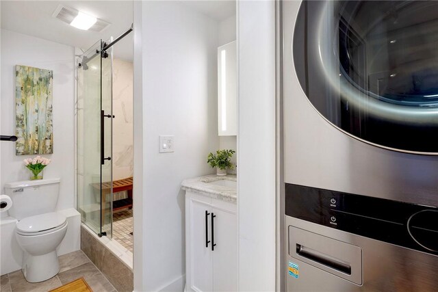 75 Pelham St Unit A, Newport, RI 02840 - bathroom with estacked washer and dryer, a stall shower, toilet, vanity, and tile patterned flooring