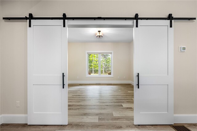 1332 S Rd, South Kingstown, RI 02879 - corridor with a barn door, light wood finished floors, and baseboards