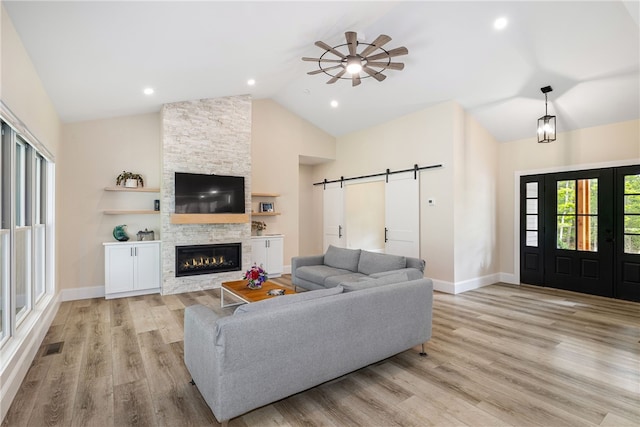 1332 S Rd, South Kingstown, RI 02879 - living room featuring a barn door, high vaulted ceiling, light wood finished floors, baseboards, and a stone fireplace