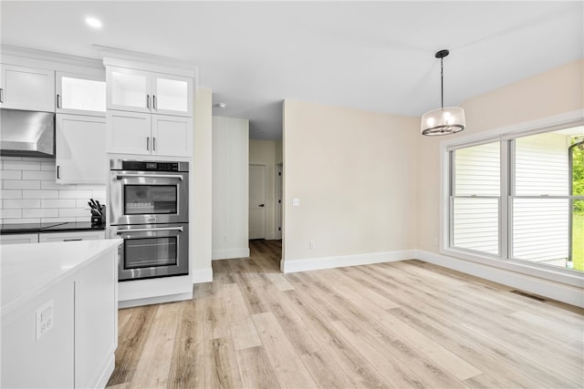 1332 S Rd, South Kingstown, RI 02879 - kitchen with double oven, wall chimney range hood, light wood finished floors, white cabinetry, and baseboards