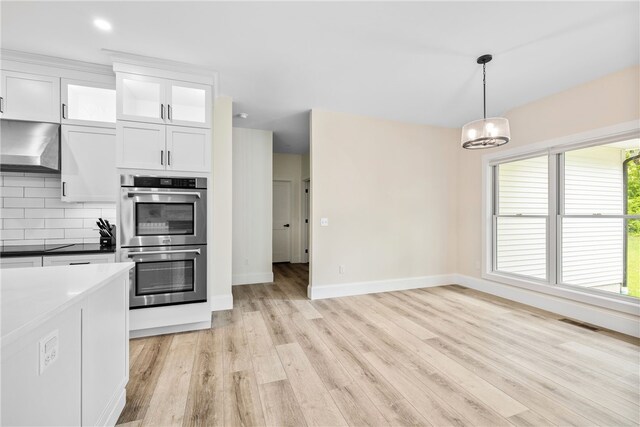 1332 S Rd, South Kingstown, RI 02879 - kitchen with double oven, wall chimney range hood, light wood finished floors, white cabinetry, and baseboards