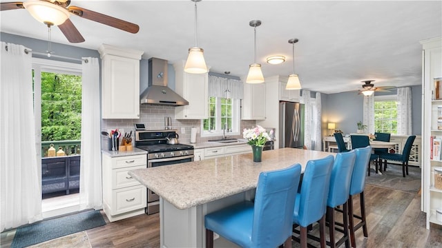 605 Gardner Rd, Exeter, RI 02822 - kitchen featuring wall chimney range hood, ceiling fan, appliances with stainless steel finishes, a sink, and a breakfast bar area