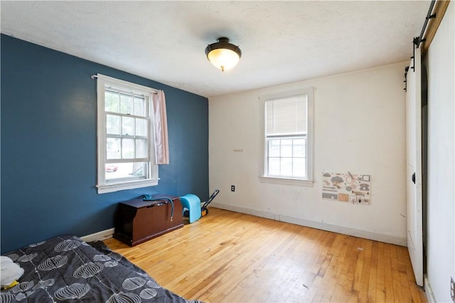 58 Edgemere Rd, Pawtucket, RI 02861 - unfurnished bedroom with a barn door, wood-type flooring, and baseboards