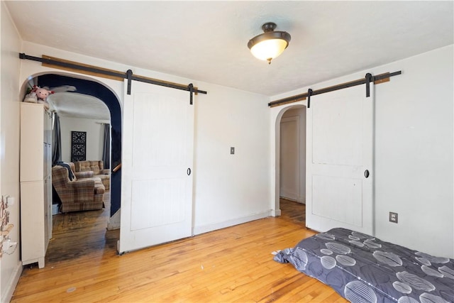 58 Edgemere Rd, Pawtucket, RI 02861 - unfurnished bedroom featuring a barn door, arched walkways, light wood finished floors, and a closet