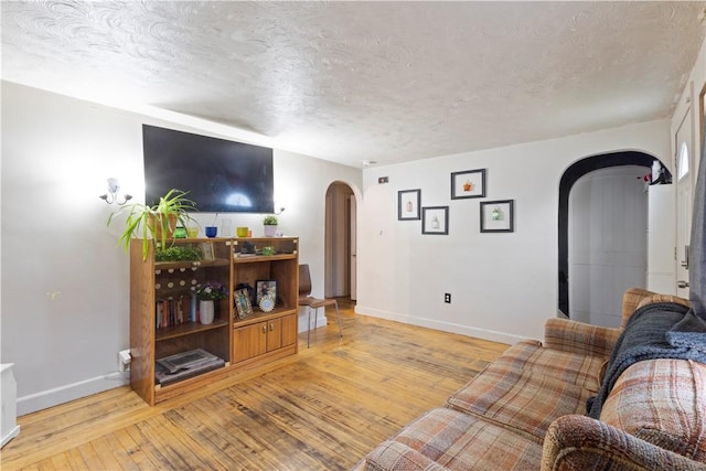 58 Edgemere Rd, Pawtucket, RI 02861 - living area featuring arched walkways, baseboards, a textured ceiling, and light wood-type flooring