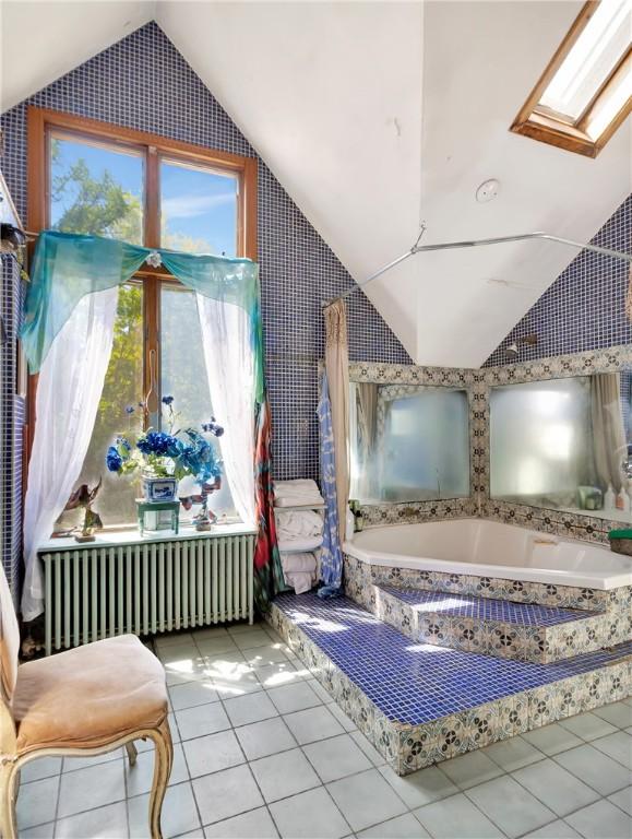 219 Nanaquaket Rd, Tiverton, RI 02878 - full bath with radiator, vaulted ceiling, tile patterned floors, a skylight, and a garden tub