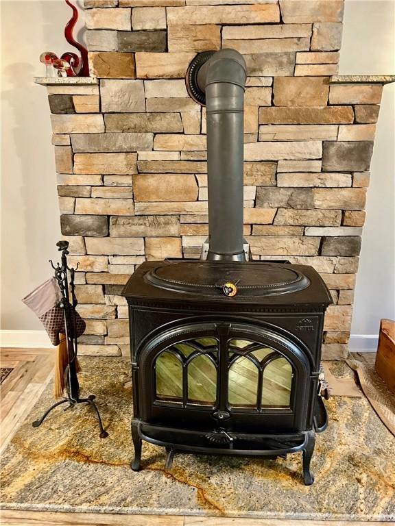 261 John Potter Rd, West Greenwich, RI 02817 - detailed view of a wood stove, baseboards, and wood finished floors