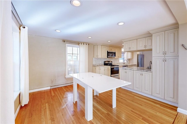 23 Sarah St, Providence, RI 02906 - kitchen featuring stainless steel appliances, a baseboard heating unit, light wood-style floors, baseboards, and decorative backsplash