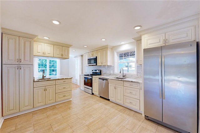 23 Sarah St, Providence, RI 02906 - kitchen with stainless steel appliances, cream cabinetry, plenty of natural light, light stone countertops, and recessed lighting