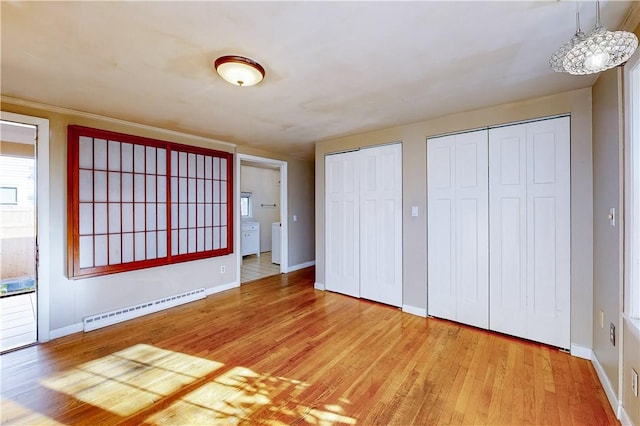 23 Sarah St, Providence, RI 02906 - unfurnished bedroom featuring a baseboard radiator, two closets, wood finished floors, and baseboards