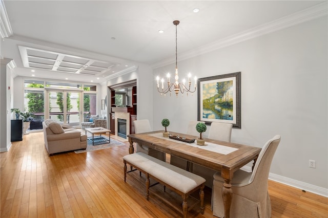 341 Thames St Unit 103, Bristol, RI 02809 - dining area featuring a chandelier, light wood-style floors, a glass covered fireplace, baseboards, and crown molding