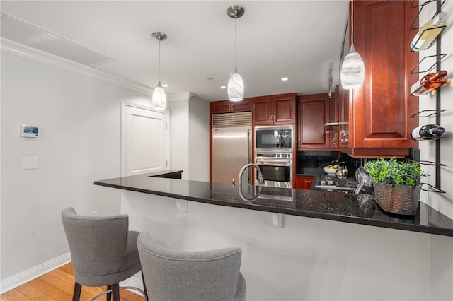 341 Thames St Unit 103, Bristol, RI 02809 - kitchen featuring built in appliances, a peninsula, light wood-style flooring, baseboards, and reddish brown cabinets