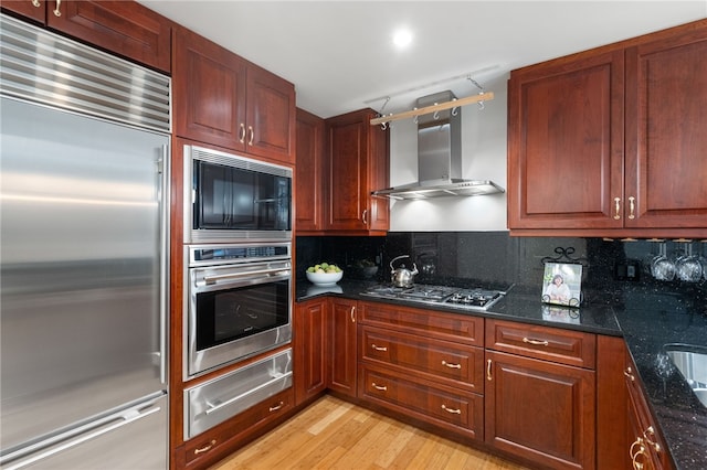 341 Thames St Unit 103, Bristol, RI 02809 - kitchen with built in appliances, a warming drawer, light wood-style floors, wall chimney range hood, and decorative backsplash
