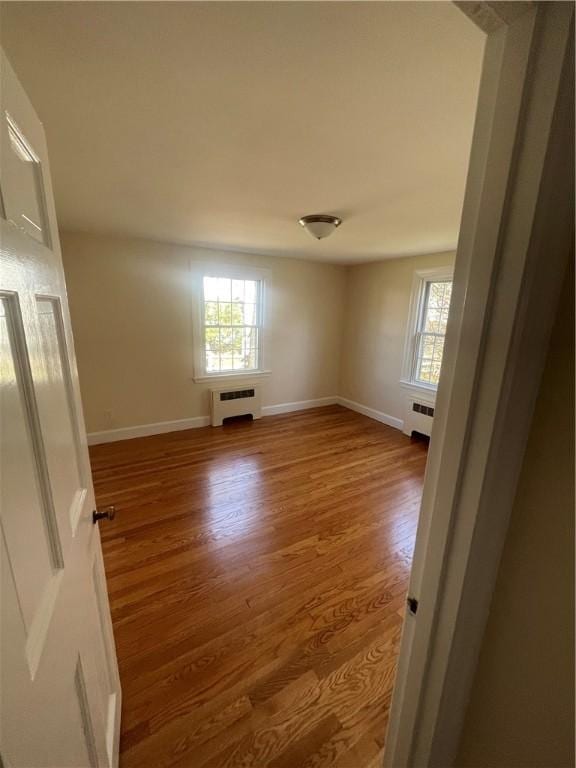 80 Frontier Rd, Warwick, RI 02889 - unfurnished room featuring radiator, plenty of natural light, and wood finished floors