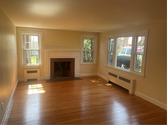 80 Frontier Rd, Warwick, RI 02889 - unfurnished living room featuring radiator, wood finished floors, baseboards, and a brick fireplace