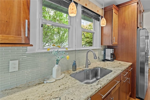 77 Friendly Rd, Cranston, RI 02910 - kitchen featuring a sink, stainless steel refrigerator with ice dispenser, brown cabinetry, tasteful backsplash, and light stone countertops