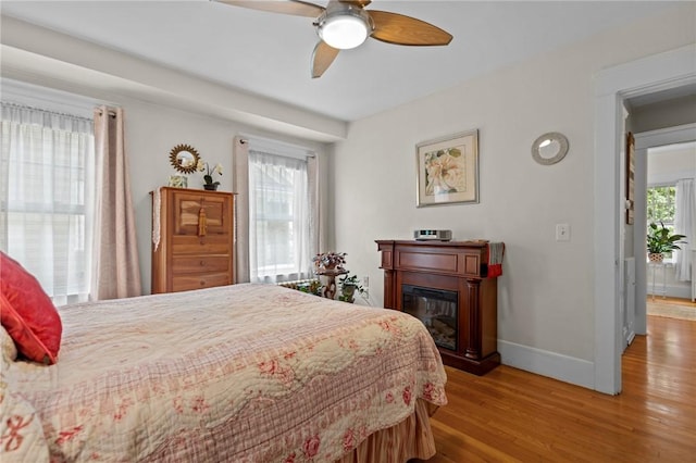 77 Friendly Rd, Cranston, RI 02910 - bedroom with wood finished floors, baseboards, a glass covered fireplace, and a ceiling fan