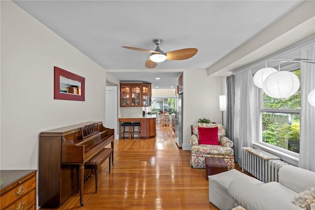 77 Friendly Rd, Cranston, RI 02910 - living room with radiator heating unit, light wood-style flooring, and ceiling fan