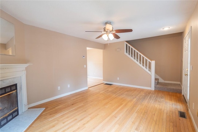 26 Noel Ct, South Kingstown, RI 02879 - unfurnished living room featuring light wood finished floors, a ceiling fan, stairs, a premium fireplace, and baseboards