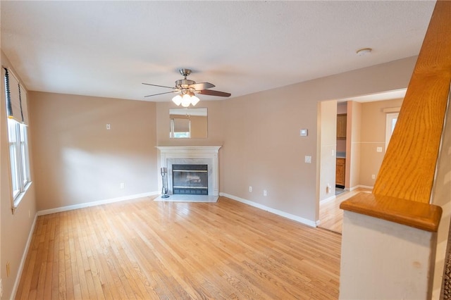 26 Noel Ct, South Kingstown, RI 02879 - unfurnished living room with light wood-type flooring, ceiling fan, baseboards, and healthy amount of natural light
