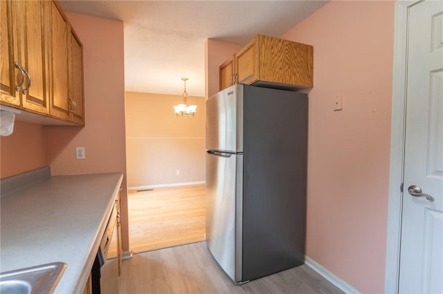 26 Noel Ct, South Kingstown, RI 02879 - kitchen with freestanding refrigerator, light wood-style flooring, brown cabinetry, and a chandelier