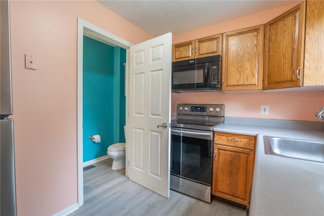 26 Noel Ct, South Kingstown, RI 02879 - kitchen with black microwave, electric range, light wood-type flooring, light countertops, and a sink