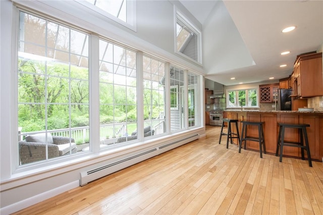 200 Miner Rd, North Kingstown, RI 02874 - kitchen featuring stainless steel range, freestanding refrigerator, baseboard heating, wall chimney exhaust hood, and light wood-type flooring