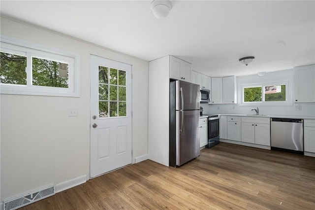 613 Prospect St, Woonsocket, RI 02895 - kitchen featuring appliances with stainless steel finishes, light countertops, wood finished floors, and white cabinets