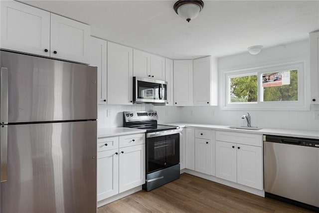 613 Prospect St, Woonsocket, RI 02895 - kitchen with appliances with stainless steel finishes, a sink, light countertops, white cabinetry, and dark wood finished floors