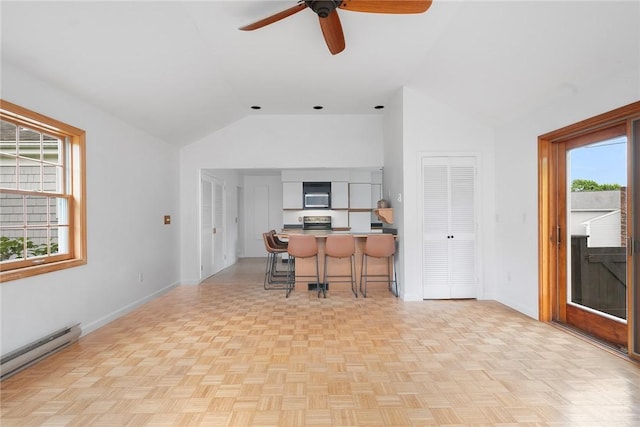 3 Ernest St, Newport, RI 02840 - kitchen with baseboard heating, lofted ceiling, a kitchen bar, a ceiling fan, and healthy amount of natural light