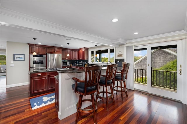 129 Sand Hill Cove Rd, Narragansett, RI 02882 - kitchen with stainless steel appliances, reddish brown cabinets, dark wood finished floors, a breakfast bar, and a warming drawer