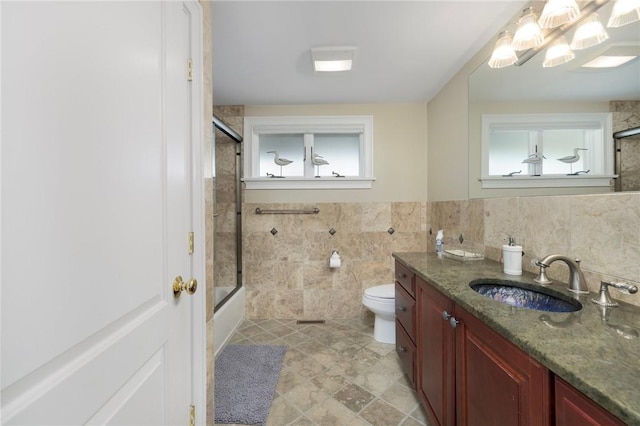 129 Sand Hill Cove Rd, Narragansett, RI 02882 - full bath featuring vanity, plenty of natural light, toilet, tile walls, and combined bath / shower with glass door