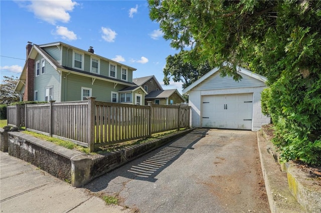 47 Cliff St, East Greenwich, RI 02818 - view of front of house featuring a chimney, asphalt driveway, a detached garage, and an outbuilding